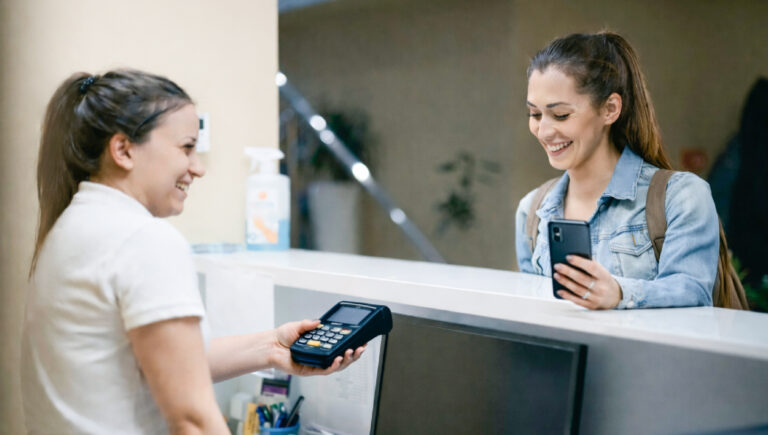 Patient preparing to pay with mobile at an office reception desk
